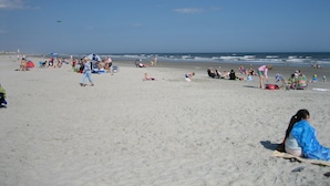 A beach with people sunbathing and swimming.