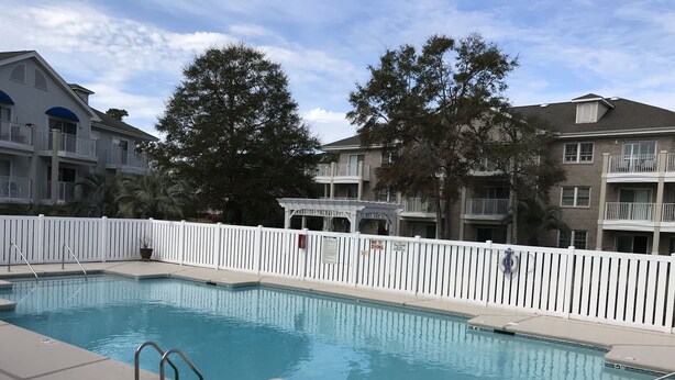 A rectangular swimming pool with a white fence, a lifeguard stand, and a pool ladder.