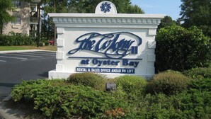 A sign for The Colony at Oyster Bay with a rental and sales office ahead on the left.