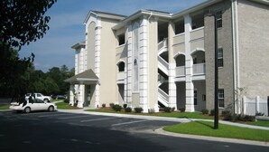A multi-story building with a symmetrical facade, multiple balconies, and a central entrance with a covered porch.