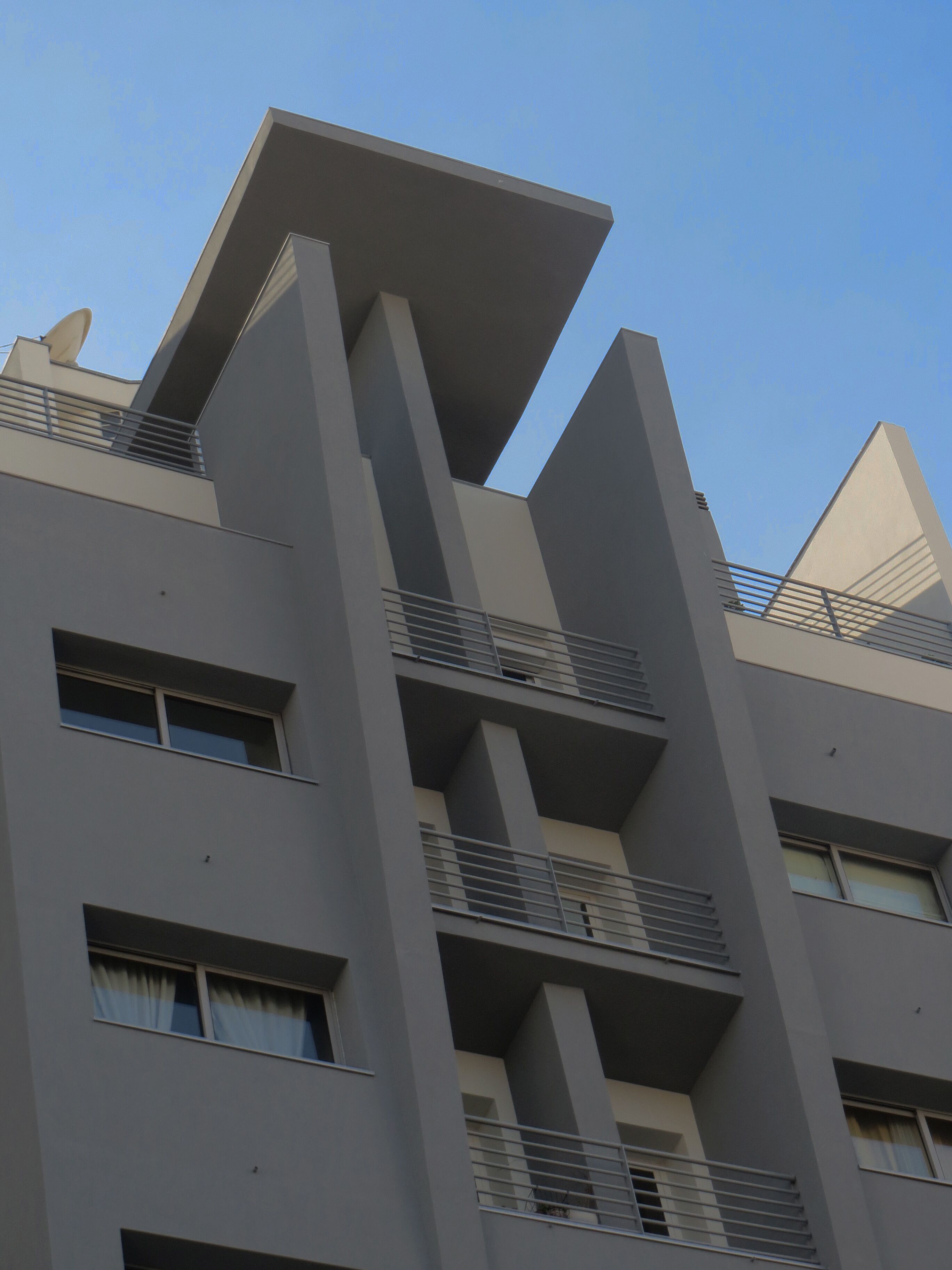 Un edificio moderno con diseño geométrico, con balcones y varios pisos.