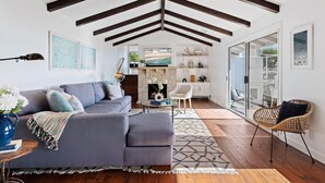 Un salon moderne avec un canapé gris, un fauteuil en osier et une cheminée.