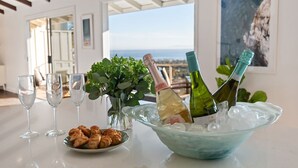 Une table avec des bouteilles de champagne, des verres et une assiette de nourriture, dans une pièce offrant une vue panoramique.