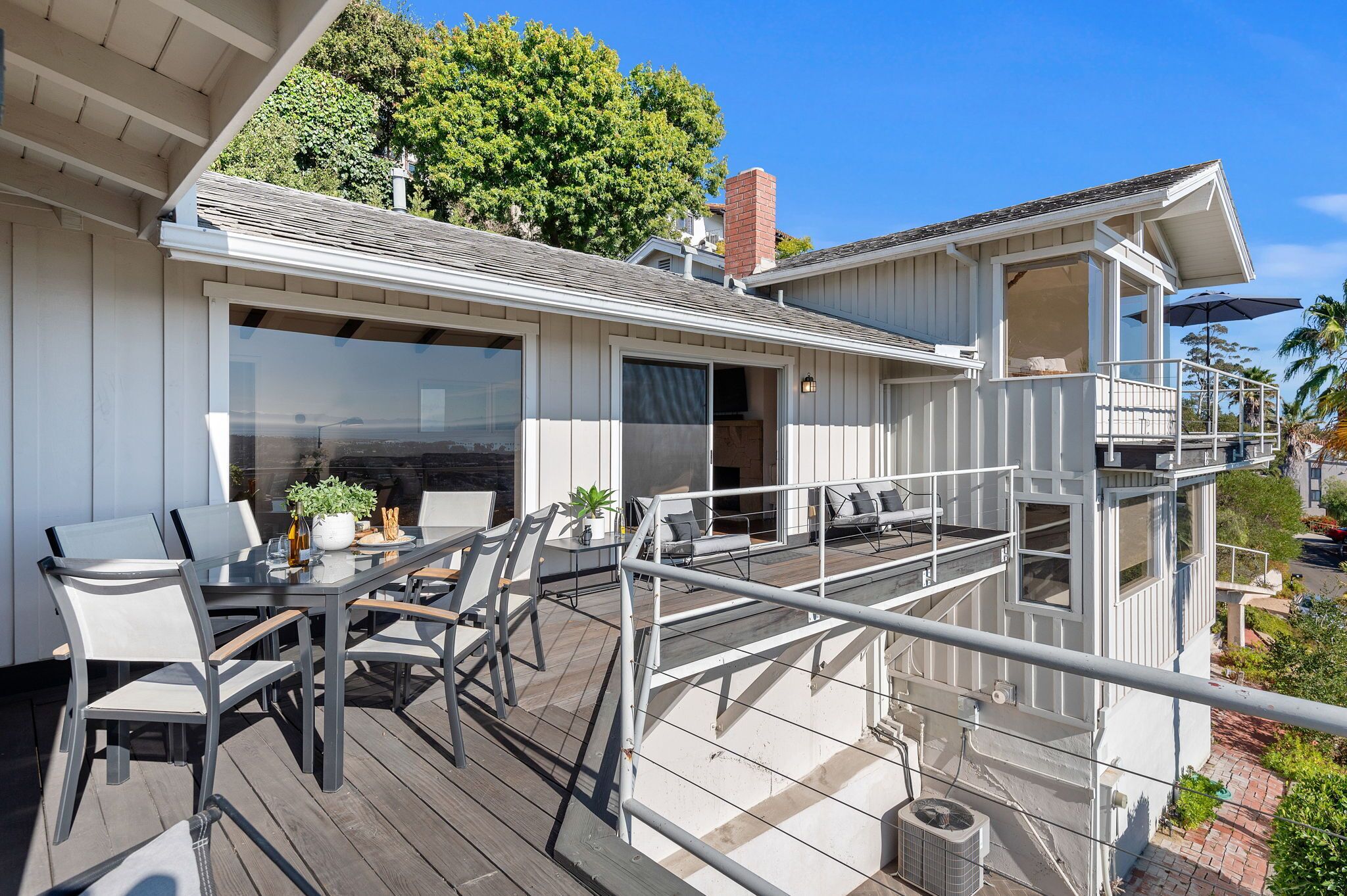 Una casa moderna con terraza, ventanas grandes y balcón.