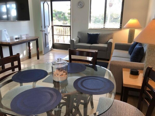 A dining area with a glass table, four chairs, and a central glass container.