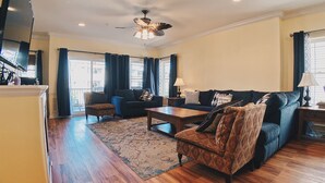 A living room with a sofa, armchair, coffee table, and a ceiling fan.