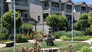 A residential building with multiple balconies, a central garden with a fountain, and surrounding greenery.
