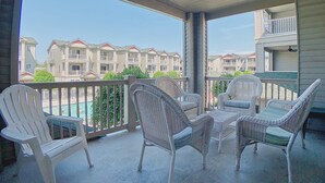 A covered balcony with wicker chairs and a pool view.