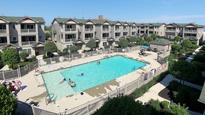 A residential building with a swimming pool, multiple balconies, and a fenced patio area.