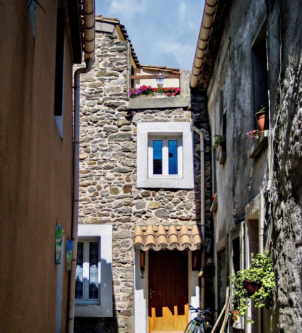 Un estrecho callejón con edificios de piedra, una puerta de madera y una bicicleta estacionada afuera.