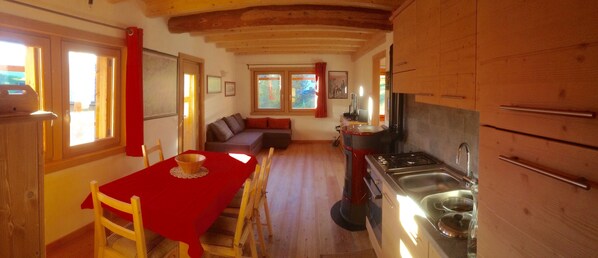 Una cocina acogedora con armarios de madera, una mesa de comedor con mantel rojo y una estufa empotrada.