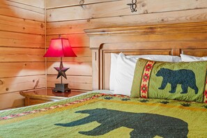 A wooden cabin-style room with a bed, a nightstand with a lamp, and a star decoration. - Premium Rustic Cabin Perfect Getaway, Private Hot Tub,Piano, Near Shows & Big Cedar, Jacuzzi Tub! (Ridgedale)