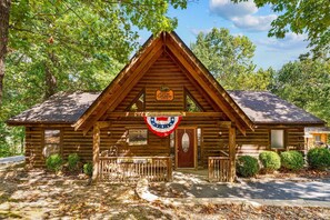 Una baita in legno con tetto a spiovente, un portico e un cartello che indica che fa parte del Great Getaway Lodge.