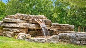 A natural rock formation with a waterfall. - Premium Rustic Cabin Perfect Getaway, Private Hot Tub,Piano, Near Shows & Big Cedar, Jacuzzi Tub! (Ridgedale)
