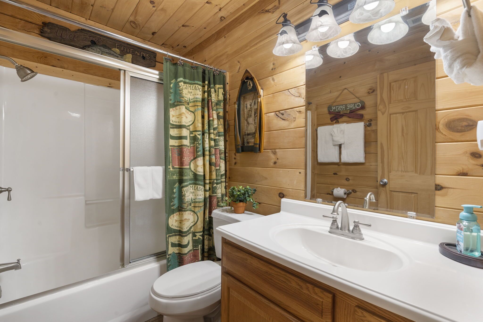 A wooden cabin bathroom with a bathtub, toilet, and sink.