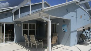 An outdoor patio with a covered seating area, a table, and chairs. - 'Lakeside Haven'  Fantastic South Facing Pool, Spa and Stunning Lakeside Views. (Kissimmee)