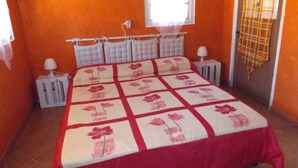 Un dormitorio con cama, ventana, radiador y puerta.