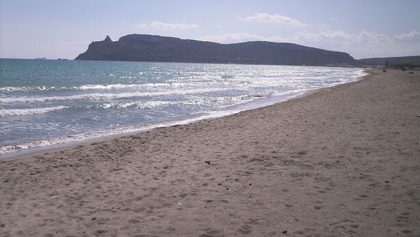 Una playa con una vista despejada del mar y colinas lejanas.