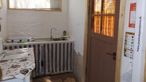 Una pequeña cocina con ventana, un lavamanos y una puerta con ventanal.