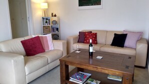 A living room with a beige sofa, a wooden coffee table, and a bookshelf. - Ten-on-French Barossa getaway (Angaston)
