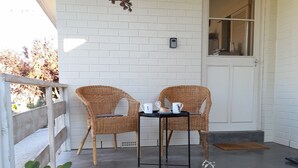 A patio with two wicker chairs, a small table, and potted plants. - Ten-on-French Barossa getaway (Angaston)