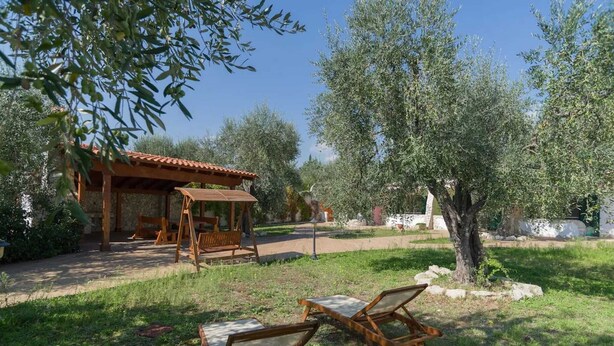 A rustic outdoor seating area with wooden furniture, a stone table, and a pergola structure. - Borghetto Tio Pepe - Trilo 6 Mandarin (Mattinata)