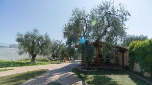 A pathway leading to a building with a pergola and a swing set in a landscaped garden. - Borghetto Tio Pepe - Trilo 6 Mandarin (Mattinata)