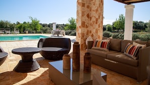 A patio with wicker furniture, a glass coffee table, and a beige sofa with striped cushions. - Villa Falgheri with swimming pool for 6 people - Itria Valley (Ostuni)