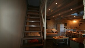 A cozy interior with a staircase leading to a loft bedroom, a dining area, and a kitchen. - Walnut Lodge, charming holiday Gite in central rural France (Pleumartin)
