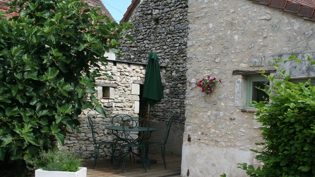 A stone building with a wooden deck, outdoor seating, and a potted plant. - Walnut Lodge, charming holiday Gite in central rural France (Pleumartin)