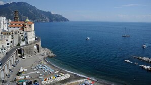 A coastal town with a historic building, a beach with umbrellas, and boats in the water. - ATRANI "CASA ROSSA" AMALFI COAST WITH SEA VIEW (ATRANI)