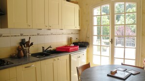 Une cuisine avec des meubles de couleur jaune clair, un plan de travail noir et une fenêtre donnant sur des arbres.