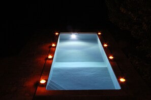 Une piscine rectangulaire dotée d’un fond en verre, entourée de lumières disposées à intervalles réguliers.