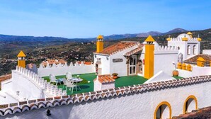 Un bâtiment blanc agrémenté de touches de jaune et bordé d’une pelouse verte, le tout entouré d’une clôture blanche surmontée d’un toit en tuiles.