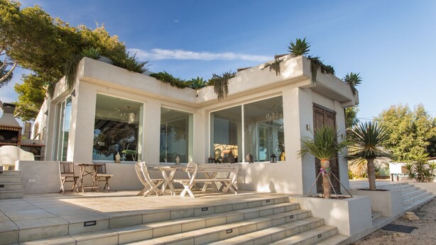 Una casa moderna con un patio, mobiliario exterior y escalones que conducen a la entrada.