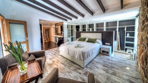 Un dormitorio moderno con una cama grande, armario empotrado y una zona de estar con una mesita de centro.