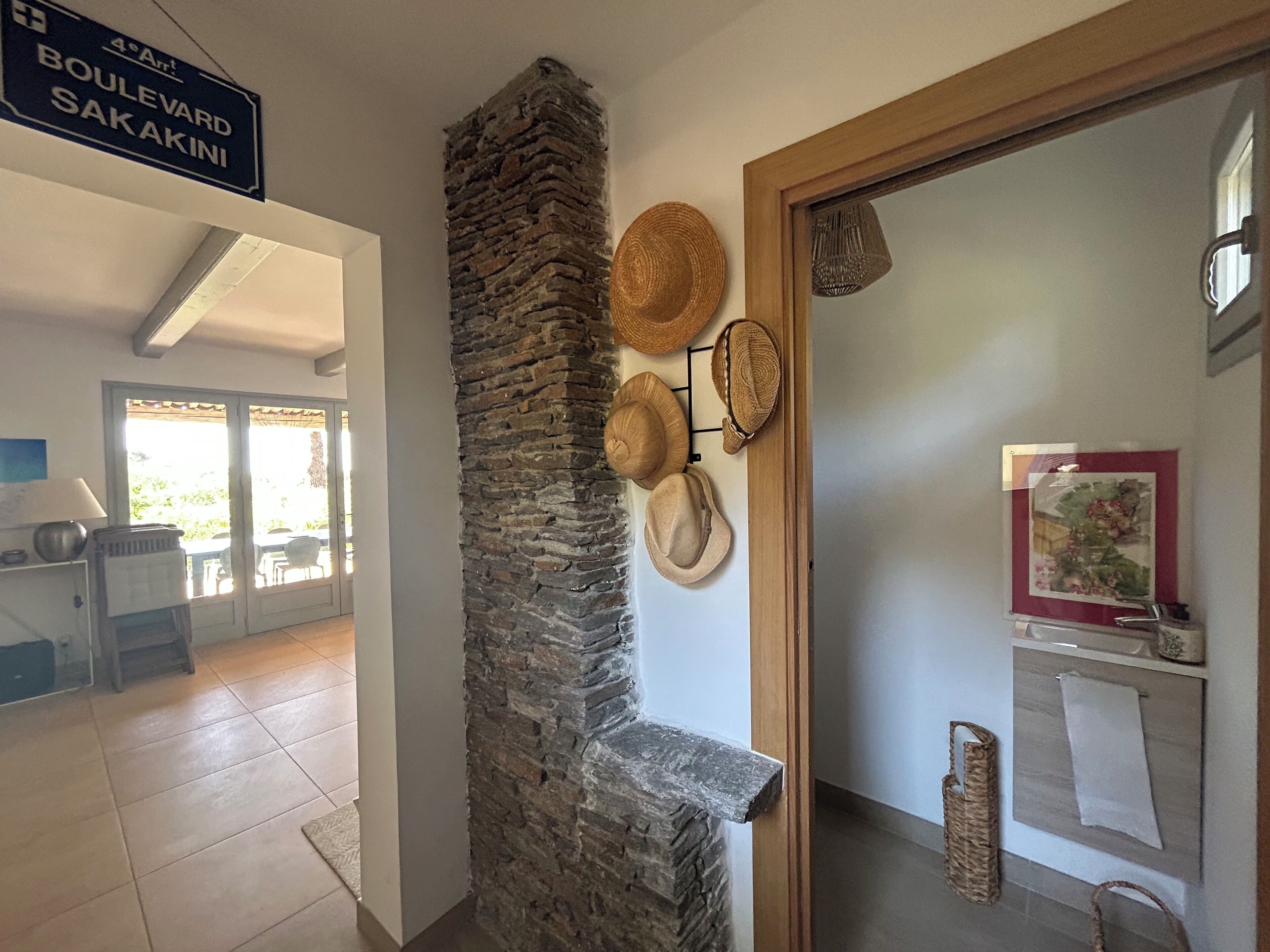 Um corredor com parede de pedra, uma porta com espelho e uma placa indicando 'Boulevard Sakakini'.
