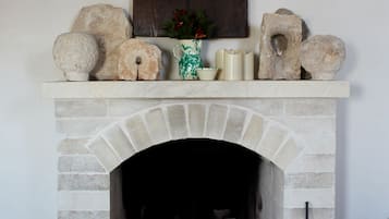 A stone fireplace with a fire, a basket, and a metal bucket.