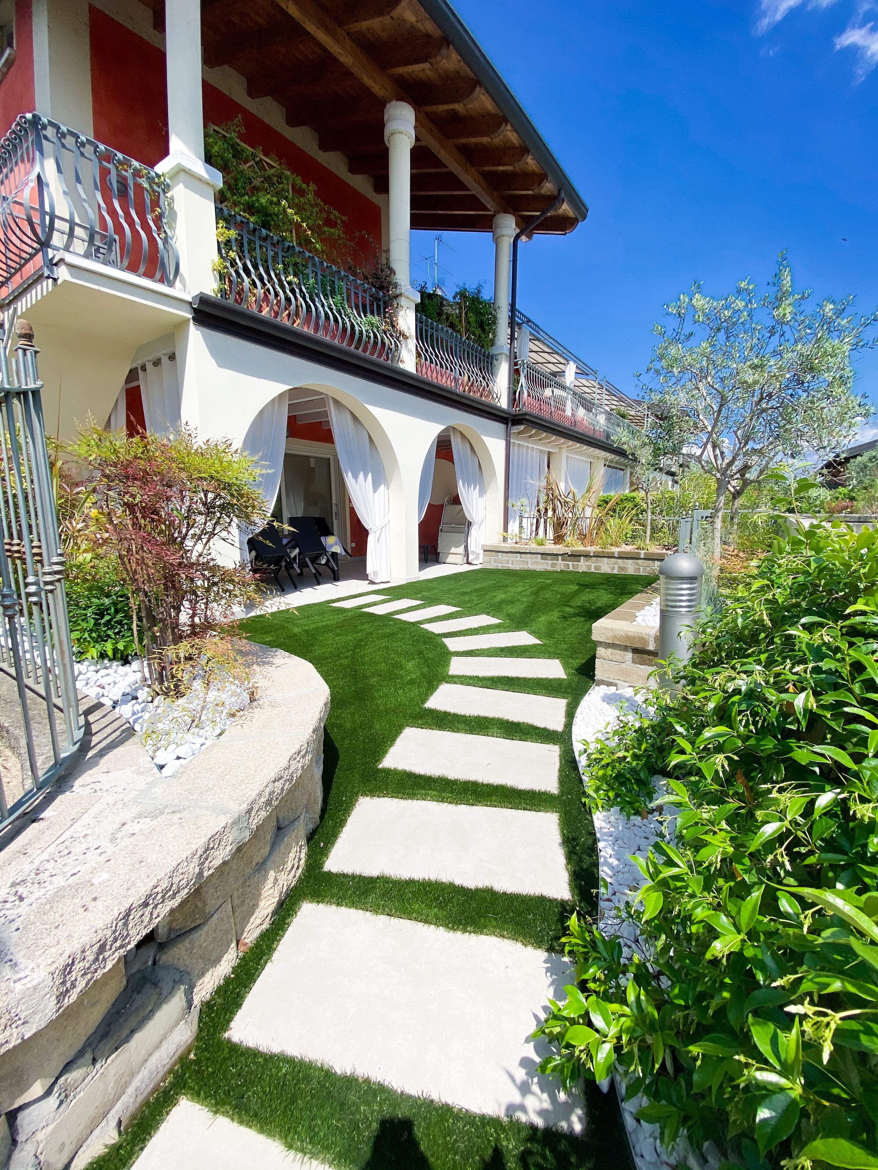 A building with a red and white facade, a stone pathway, and green landscaping.