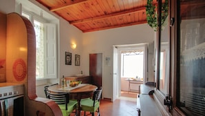 A kitchen with a stove, a dining table with chairs, and a window with curtains.