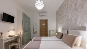 A modern hotel room with a bed, desk, and TV.