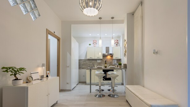 A modern kitchen with white cabinets, a central island, and pendant lighting.