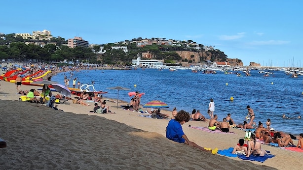 A beach with people sunbathing and swimming, boats in the water, and buildings in the background. - P2131- FANTASTIC VIEWS, AIR CONDITIONING, POOL AND WIFI (Sant Feliu de Guixols)