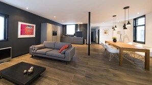 A modern living room with a grey sofa, a coffee table, and a dining area with a wooden table and chairs. - Villa Antonius Amsterdam (Ouderkerk aan de Amstel)