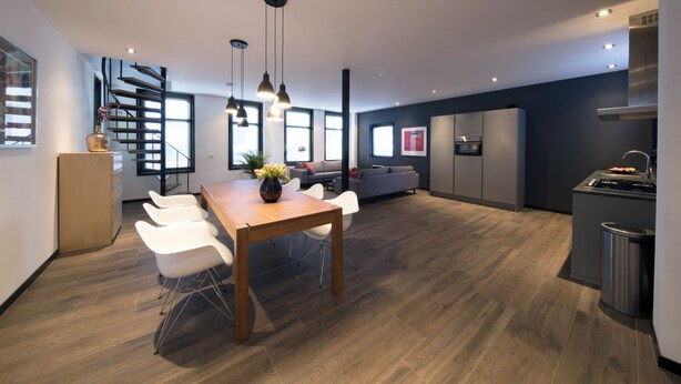 A modern kitchen with a dining area, wooden flooring, and a staircase. - Villa Antonius Amsterdam (Ouderkerk aan de Amstel)