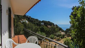 A balcony with a table and chairs, overlooking a coastal landscape with trees and houses. - Club Villamar - Charming villa in peaceful surroundings with private pool and fabulous sea views (Tamariu)