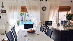 Ruokailutila, jossa on kahdelle katettu pöytä, hedelmäkulho ja seinällä oleva kello.