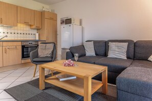 A compact living space with a kitchenette, a sofa, a small table, and a chair. - A snug nest for 2: The ground floor apartment is charming and cozy arra (Carolinensiel)