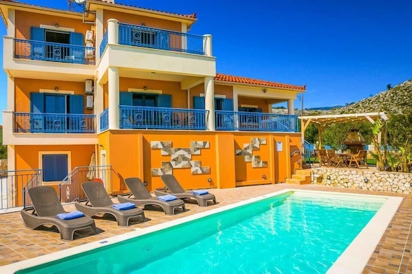 A hotel with a pool, multiple balconies, and outdoor seating.