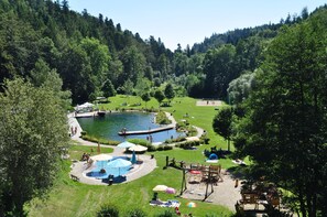 Un parque con un estanque, zonas de picnic y un área de juegos.
